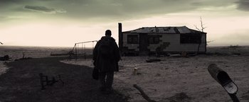 Movie still from “The Book of Eli” (2010), directed by Allen Hughes – A man walking on a dirt road near a house; Wide shot, Low angle