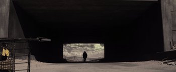 Movie still from “The Book of Eli” (2010), directed by Allen Hughes – A man standing in a tunnel looking out at the sky; Extreme Wide shot, Low angle