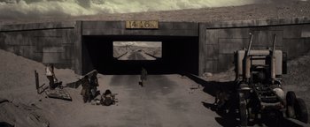 Movie still from “The Book of Eli” (2010), directed by Allen Hughes – A man standing on the side of a road near a bridge; Extreme Wide shot, High angle