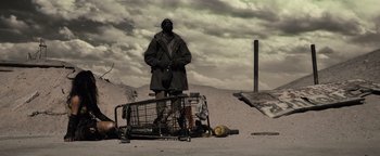 Movie still from “The Book of Eli” (2010), directed by Allen Hughes – A man standing in the dirt with a shopping cart; Wide shot, Low angle