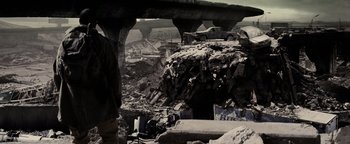 Movie still from “The Book of Eli” (2010), directed by Allen Hughes – A man standing in the middle of a rubble covered area; Wide shot, Over the shoulder angle