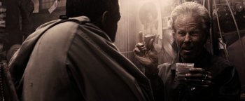 Movie still from “The Book of Eli” (2010), directed by Allen Hughes – A man taking a picture with a cell phone; Close Up shot, Low angle