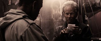 Movie still from “The Book of Eli” (2010), directed by Allen Hughes – A man looking at another man holding something in his hand; Close Up shot, Over the shoulder angle