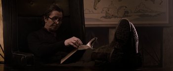 Movie still from “The Book of Eli” (2010), directed by Allen Hughes – A man sitting at a table reading a book; Medium shot, Low angle