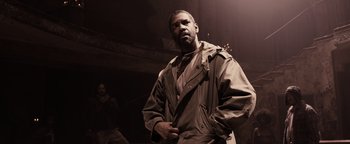 Movie still from “The Book of Eli” (2010), directed by Allen Hughes – A man standing in the dark wearing a jacket; Medium shot, Low angle