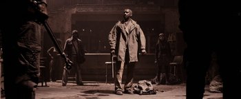 Movie still from “The Book of Eli” (2010), directed by Allen Hughes – A man standing next to a bag on the ground; Wide shot, Low angle