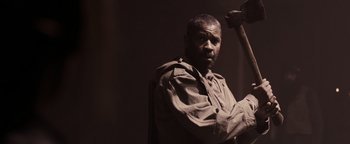 Movie still from “The Book of Eli” (2010), directed by Allen Hughes – A man holding a hammer in a dark room; Medium shot, Over the shoulder angle