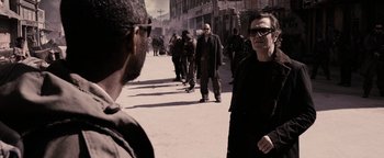 Movie still from “The Book of Eli” (2010), directed by Allen Hughes – A group of people walking down a street; Medium shot, Over the shoulder angle