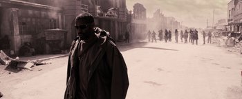 Movie still from “The Book of Eli” (2010), directed by Allen Hughes – A man walking down a street with a crowd of people; Wide shot, Over the shoulder angle