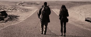 Movie still from “The Book of Eli” (2010), directed by Allen Hughes – A man and a woman walking down the middle of a road; Wide shot, Low angle