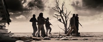 Movie still from “The Book of Eli” (2010), directed by Allen Hughes – A group of men standing on top of a dirt field; Wide shot, Low angle