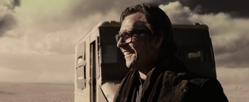 Movie still from “The Book of Eli” (2010), directed by Allen Hughes – A person wearing glasses near a bus; Close Up shot, Low angle