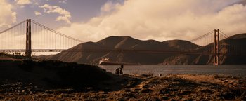 Movie still from “The Book of Eli” (2010), directed by Allen Hughes – A person sitting on the ground near a body of water; Extreme Wide shot, Low angle