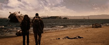 Movie still from “The Book of Eli” (2010), directed by Allen Hughes – A man walking on the beach near the water; Extreme Wide shot, High angle