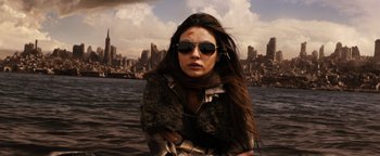 Movie still from “The Book of Eli” (2010), directed by Allen Hughes – A woman with long brown hair wearing sunglasses and a fur coat; Close Up shot, Low angle