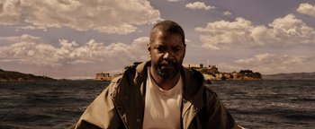 Movie still from “The Book of Eli” (2010), directed by Allen Hughes – A man with a beard is standing in front of a body of water; Close Up shot, Low angle