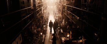 Movie still from “The Book of Eli” (2010), directed by Allen Hughes – A couple of people walking through a room filled with lots of stuff; Wide shot, High angle