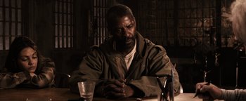 Movie still from “The Book of Eli” (2010), directed by Allen Hughes – A man sitting at a table with a glass of wine; Close Up shot, Over the shoulder angle
