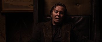 Movie still from “The Book of Eli” (2010), directed by Allen Hughes – A man sitting in a chair wearing a fur coat; Close Up shot, Low angle