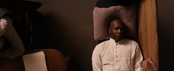 Movie still from “The Book of Eli” (2010), directed by Allen Hughes – A man sitting in a chair with his head on a pillow; Medium shot, High angle