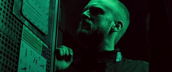 Movie still from “Pandorum” (2009), directed by Christian Alvart – A man with a goatee and a black shirt; Close Up shot, Low angle