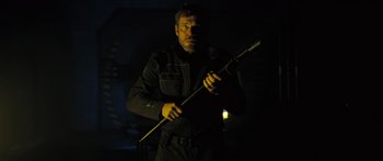 Movie still from “Pandorum” (2009), directed by Christian Alvart – A man holding a stick in the dark; Medium shot, Low angle