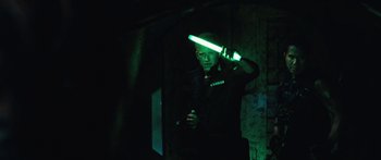 Movie still from “Pandorum” (2009), directed by Christian Alvart – A man holding a light saber in the dark; Medium shot, Over the shoulder angle
