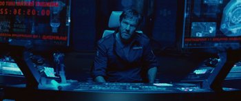 Movie still from “Pandorum” (2009), directed by Christian Alvart – A man sitting at a computer desk in a dark room; Medium shot, Low angle