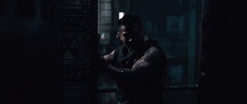 Movie still from “Pandorum” (2009), directed by Christian Alvart – A man in a black shirt is standing in the dark; Medium shot, Low angle
