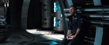 Movie still from “Pandorum” (2009), directed by Christian Alvart – A man holding a gun sitting in a room; Medium shot, High angle