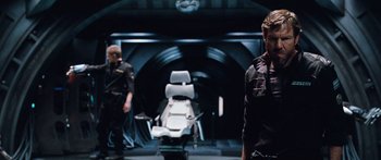 Movie still from “Pandorum” (2009), directed by Christian Alvart – Two men standing in front of an operating room; Medium shot, Over the shoulder angle