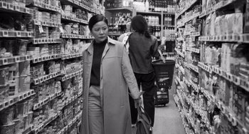 Movie still from “Paris, 13th District” (2021), directed by Jacques Audiard – A woman walking through a grocery store aisle; Medium shot, Low angle