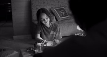 Movie still from “Paris, 13th District” (2021), directed by Jacques Audiard – A woman sitting at a table with a plate of food; Medium shot, Over the shoulder angle