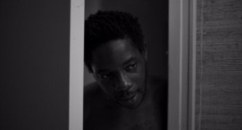 Movie still from “Paris, 13th District” (2021), directed by Jacques Audiard – A black and white photo of a man looking at the camera; Close Up shot, Low angle