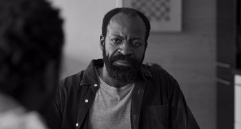 Movie still from “Paris, 13th District” (2021), directed by Jacques Audiard – A black and white photo of a man with a beard; Close Up shot, Low angle