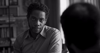 Movie still from “Paris, 13th District” (2021), directed by Jacques Audiard – A black and white photo of a man in a shirt; Close Up shot, Over the shoulder angle