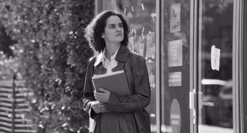 Movie still from “Paris, 13th District” (2021), directed by Jacques Audiard – A black and white photo of a woman holding a book; Medium shot, Low angle