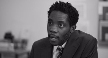 Movie still from “Paris, 13th District” (2021), directed by Jacques Audiard – A black and white photo of a man wearing a suit and tie; Close Up shot, High angle