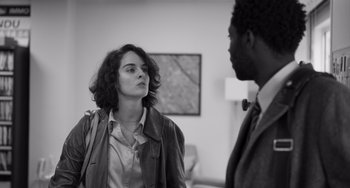 Movie still from “Paris, 13th District” (2021), directed by Jacques Audiard – A woman and a man are talking in a room; Medium shot, Over the shoulder angle