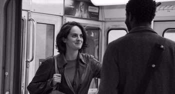 Movie still from “Paris, 13th District” (2021), directed by Jacques Audiard – A black and white photo of a woman talking to a man on a train; Medium shot, Over the shoulder angle