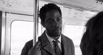 Movie still from “Paris, 13th District” (2021), directed by Jacques Audiard – A black and white photo of a man on a bus; Close Up shot, Low angle