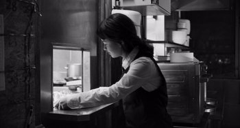 Movie still from “Paris, 13th District” (2021), directed by Jacques Audiard – A woman working in a kitchen preparing a meal; Medium shot, Low angle