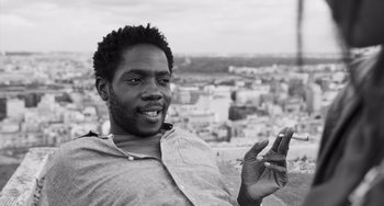 Movie still from “Paris, 13th District” (2021), directed by Jacques Audiard – A black and white photo of a man holding a cell phone; Close Up shot, Low angle
