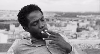Movie still from “Paris, 13th District” (2021), directed by Jacques Audiard – A black and white photo of a man smoking a cigarette; Close Up shot, Low angle