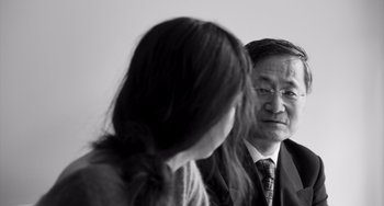 Movie still from “Paris, 13th District” (2021), directed by Jacques Audiard – An older man and a young woman are looking at each other; Close Up shot, Over the shoulder angle
