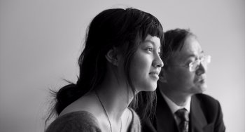 Movie still from “Paris, 13th District” (2021), directed by Jacques Audiard – A young woman with bangs is looking at the camera; Close Up shot, Over the shoulder angle