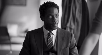 Movie still from “Paris, 13th District” (2021), directed by Jacques Audiard – A black and white photo of a man wearing a suit and tie; Close Up shot, Low angle