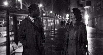 Movie still from “Paris, 13th District” (2021), directed by Jacques Audiard – A man and a woman standing next to each other on a sidewalk; Medium shot, Over the shoulder angle