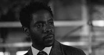 Movie still from “Paris, 13th District” (2021), directed by Jacques Audiard – A black and white photo of a man wearing a suit and tie; Close Up shot, Low angle