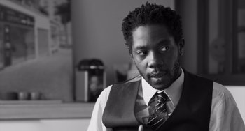 Movie still from “Paris, 13th District” (2021), directed by Jacques Audiard – A black and white photo of a man wearing a vest and a tie; Close Up shot, Low angle